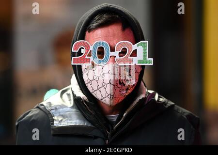 New York, USA. 31st Dec, 2020. A man wearing 2021 New Year themed eyewear walks down down 8th Avenue and 42nd Street as people are kept from accessing Times Square due to the ongoing Coronavirus pandemic, New York, NY, December 31, 2020. The traditional gathering of New Year's Eve revelers in Times Square has been restricted due to the COVID-19 surge, as the United States sets new daily records in the number of deaths and hospitalizations due to Coronavirus infections. (Photo by Anthony Behar/Sipa USA) Credit: Sipa USA/Alamy Live News Stock Photo