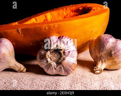 Orange pumpkin and garlic vegetable on a black background. Harvest vegetables. Head of garlic. Halloween orange pumpkin. Halloween holiday. Agricultur Stock Photo