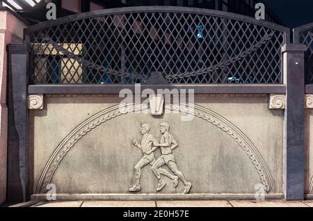 tokyo, japan - november 02 2020: Close up on a stone relief depicting athletes practicing marathon race on the Olympic Bridge of Harajuku named Gorinb Stock Photo