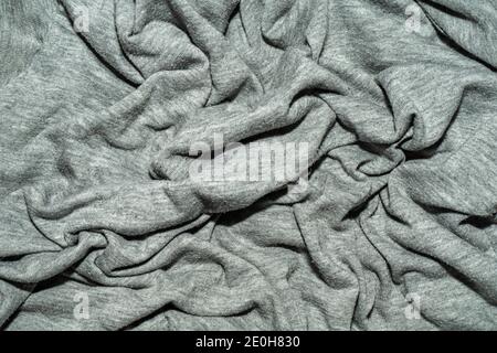 the fabric is gray with many folds. Crumpled cotton T-shirt fabric. Stock Photo