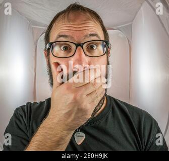 A bearded horrified looking man with black glasses Stock Photo