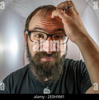 A bearded horrified looking man with black glasses Stock Photo