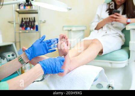 Pedicure dead skin remover foot rasp woman. Professional hardware using electric machine. Patient on medical pedicure procedure, visiting podiatrist. Stock Photo