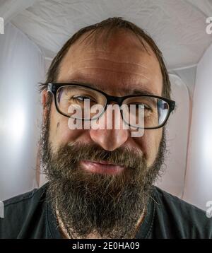 happy bearded man in black leather jacket pointing and using smartphone ...