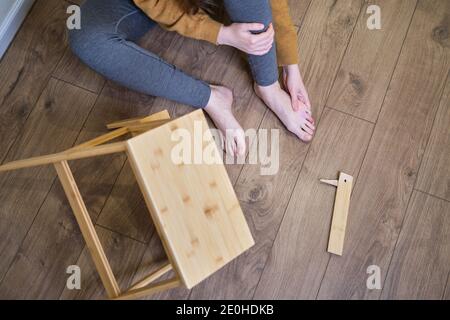 A man holds on to his injured leg after falling from a wooden ladder. Safety issues at work at height due to disruption to work at home Stock Photo