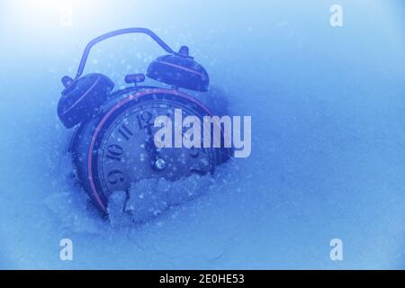 Alarm clock in snow, on bright night in light of moon at twelve clock Stock Photo