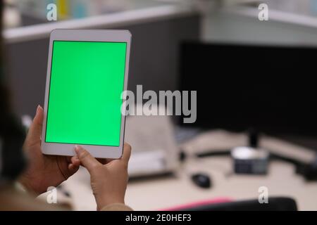 over the shoulder view of woman using green screen tablet in office Stock Photo