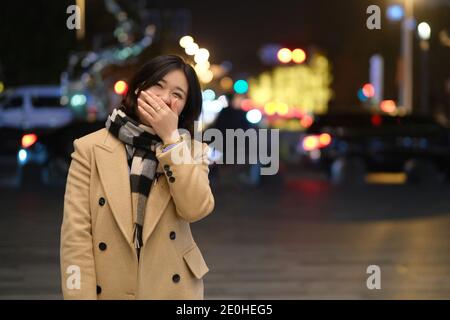 mid shot of one beautiful Asian young woman laughing behind hand at night. Stock Photo