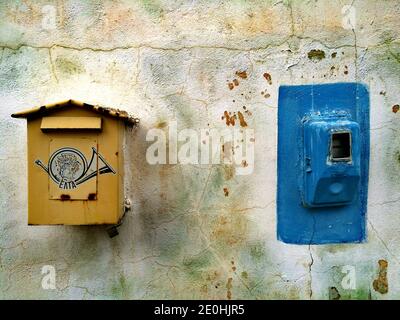 Old yellow postal box and blue electricity meter on a colourful wall at Monemvasia, Greece Stock Photo