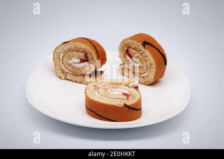 Sliced sweet roll. White plate. Close-up. On a light gray background. Stock Photo