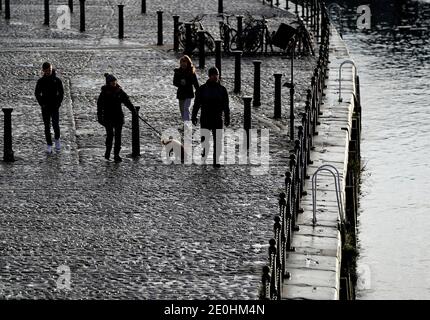 People walk past the River Ouse in York. More than three quarters of England's population is being ordered to stay at home to stop the spread of coronavirus. Stock Photo