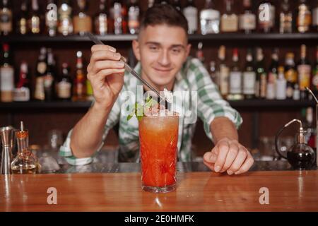 Close up of a delicious coktail with ice, professional bartender is decorating. Barman working at his restaurant, preparing a drink for customer Stock Photo