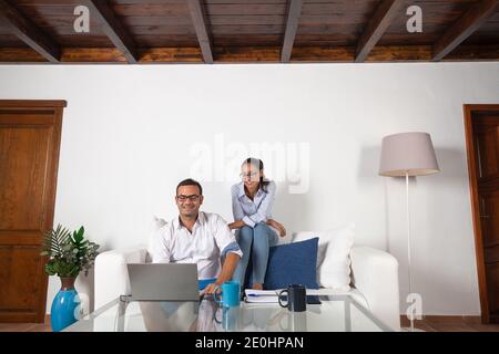 Young adult couple looking at the laptop in the living room at home. Stock Photo