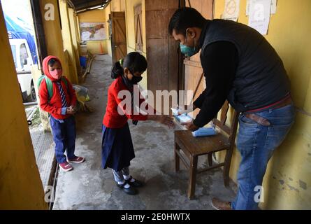 December 31, 2020, Guwahati, Assam, India: A Teacher apply sanitizer in the hands of a student before he enter inside the class room  after the Primary school re open in the state from today after  nine months due to coranavirus pamdemics  at Uzanbazar Jahaj Ghat primary school in Guwahati Assam India  on Friday 1st January 2021. (Credit Image: © Dasarath Deka/ZUMA Wire) Stock Photo