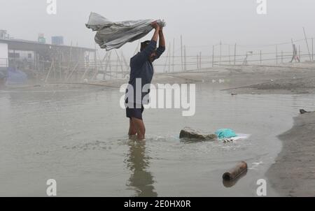 December 31, 2020, Guwahati, Assam, India: A washer man washes clothes in river Brahmaputra on a foggy morning in Guwahati Assam India on Friday 1st January 2021. River Brahmaputra is one of Asia's largest rivers, which flows from China's Tibet region and enter India  (Credit Image: © Dasarath Deka/ZUMA Wire) Stock Photo