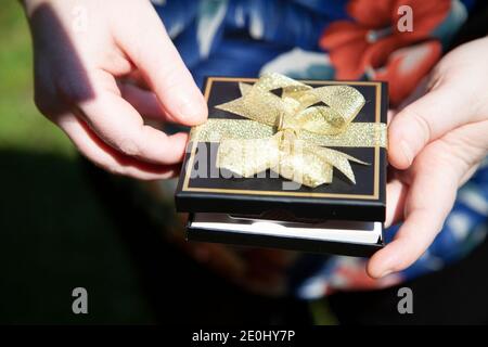 Woman opening a black gift box with a gift card in it Stock Photo