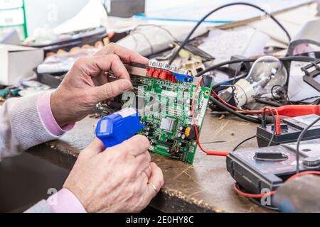Close up of the hands men hold tool repairs electronics manufacturing Services, Manual Assembly Of Circuit Board Soldering. Stock Photo