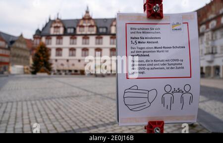 Coburg, Germany. 01st Jan, 2021. Only a few people walk through Coburg's market square while a sign indicates that masks are mandatory. The city of Coburg has tightened its Corona regulations because of further rising infection figures. From this Thursday (31.12.2020), only two specifically named households with a maximum of five adults are allowed to visit each other. Credit: Nicolas Armer/dpa/Alamy Live News Stock Photo