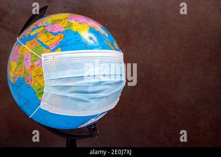 Earth globe with surgical face mask. The concept of the global problem of corona virus prevention and treatment, travel during a pandemic. Selective f