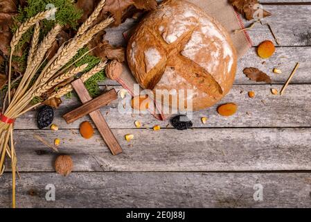 Traditional food for orthodox Christmas eve. Yule log or badnjak, bread, cereals, dried fruits and wooden cross on wooden table. Concept celebration o Stock Photo