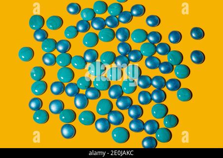 Blue and turquoise glass pebbles on a yellow background. Stock Photo