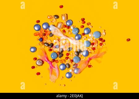 Multi coloured beads and organza ribbons on yellow background Stock Photo