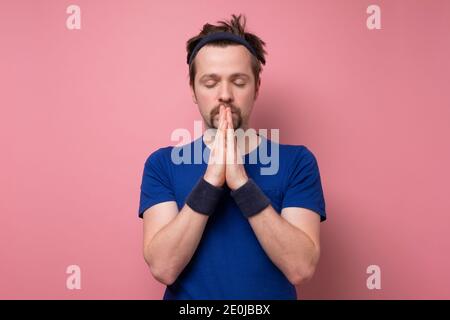 Sporty caucasian funny man meditating on yoga class. Studio shot on pink wall. Stock Photo