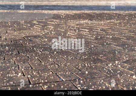 De-icing chemical reagent on pavement in winter time, focus on foreground. Pavement is sprinkled with technical salt will make the road safe Stock Photo
