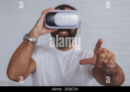 Mature bearded businessman smiling, wearing 3d virtual reality glasses at the office, reaching out to the camera with his hand. Handsome man using vr Stock Photo