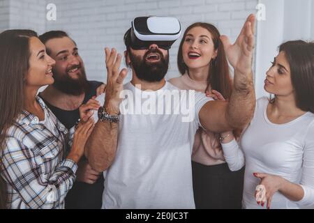 Creative business team using virtual reality glasses at the office. Bearded mature man wearing 3d vr headset, his colleagues surrounding him. Teamwork Stock Photo
