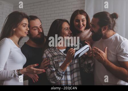 Beautiful woman smiling, talking to her friends after using virtual reality glasses. Group of creative business people discussing vr 3d goggles. Teamw Stock Photo