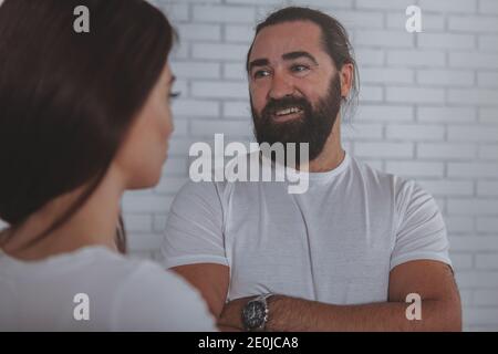 Handsome cheerful mature businessman smiling joyfully, talking to his female colleague. Happy bearded man enjoying chatting to his female friend at wo Stock Photo