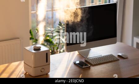 Close up of aroma oil diffuser on the table at home, steam from the air humidifier. Ultrasonic technology, increase in air humidity indoors, comfortab Stock Photo
