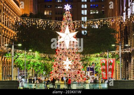 Decorated illuminated christmas tree on Martin place in City of Sydney at sunset . Stock Photo