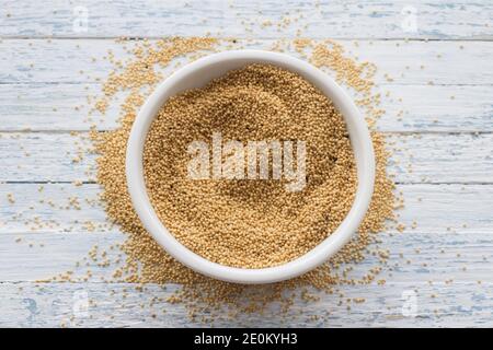 Raw amaranth seeds in a ceramic bowl on a light blue background, top view, selective focus Stock Photo