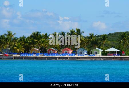 The distance view of beach chairs in front of colorful bungalows on the island of Princess Cays, Bahamas Stock Photo