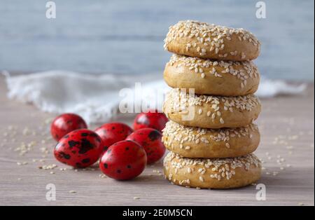 Traditional Greek Easter cookies with sesame seeds and colored eggs on the wooden table, selective focus, free space Stock Photo