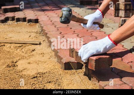 worker laying red concrete paving blocks. Stock Photo