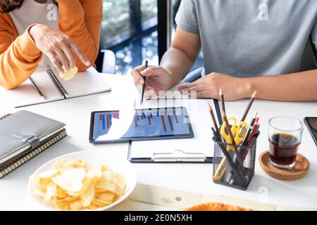 Happy business team workers talking about project and sharing meal enjoying having fun at work Having Meeting Eating Pizza and potato chips. Stock Photo