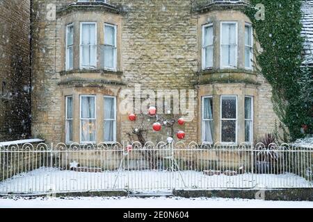 Cotswold stone house on the high street in the snow at christmas. Shipton Under Wychwood, Cotswolds, Oxfordshire, England Stock Photo