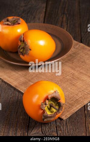 Ripe persimmon fruits on rustic wooden table Stock Photo