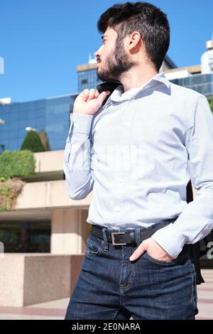 Young business man portrait looking back with buildings in the background. Businessman in a urban street of a city. Stock Photo