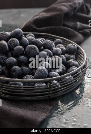 Closeup view of a metallic cooling rack where there is a pile of fresh and wet blueberries. Light drops of water are falling. Stock Photo