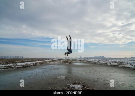 Mortara -12/29/2020: woman jumping happily in a rice field landscape in winter in north italy Stock Photo