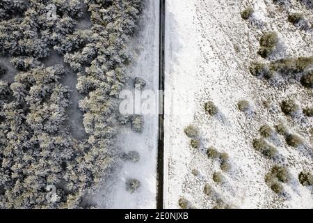 Aerial view of empty snow covered road in winter forest. High quality photo.