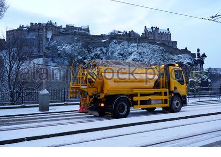 Edinburgh, Scotland, UK. 2nd Jan 2021. Snow falls just before sunrise in the city centre. Gritter spreading salt on Princes Street. Credit: Craig Brown/Alamy Live News Stock Photo