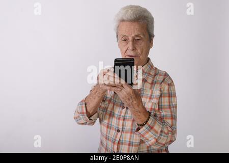 Elderly woman looking at her smartphone screen in amazement. Stock Photo