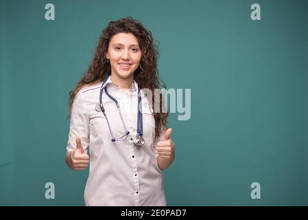 Doctor female shows good sign on green background witn copy space . health concept Stock Photo