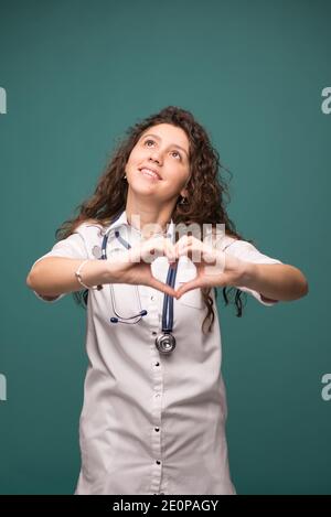 Doctor female shows good sign on green background witn copy space . health concept . vertical photo. Stock Photo