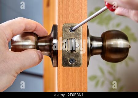Fixing the loose doorknob or door handle. Stock Photo
